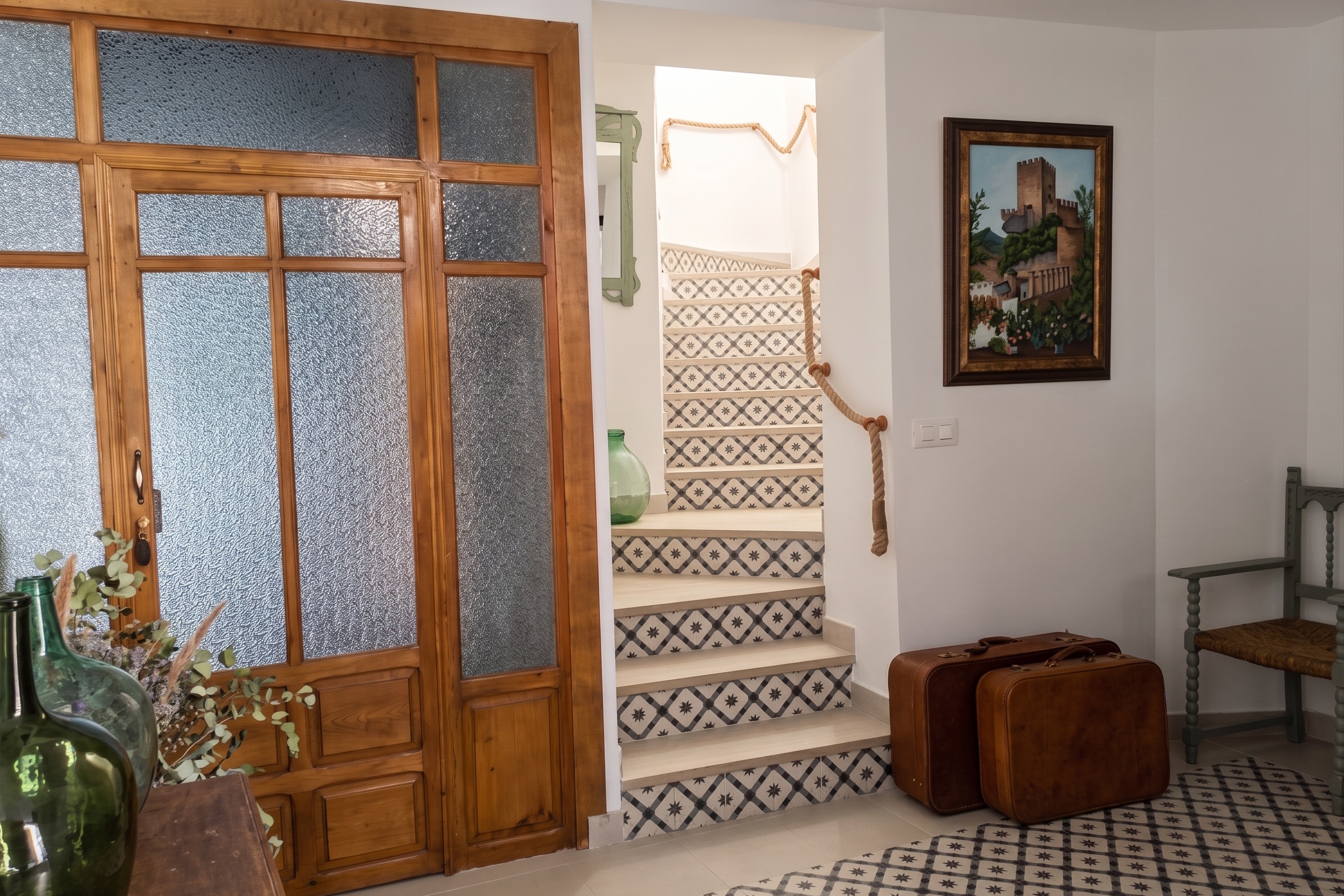 Zaguán de la casa: escalera de baldosa hidráulica, damajuanas y maletas de cuero