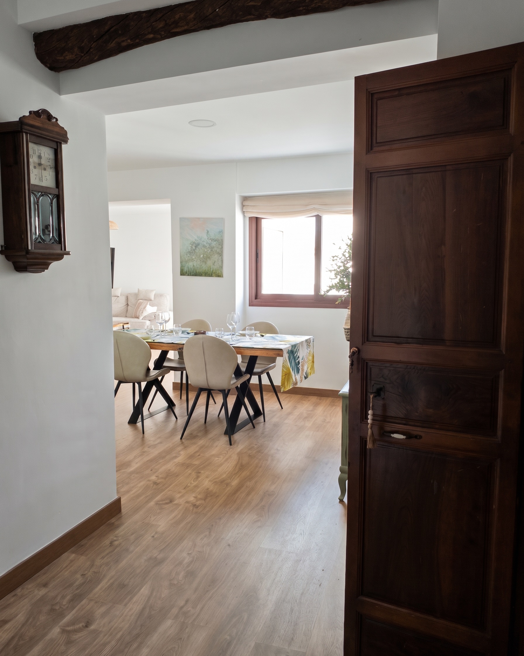 Viga de madera vista y reloj antiguo, con el comedor al fondo