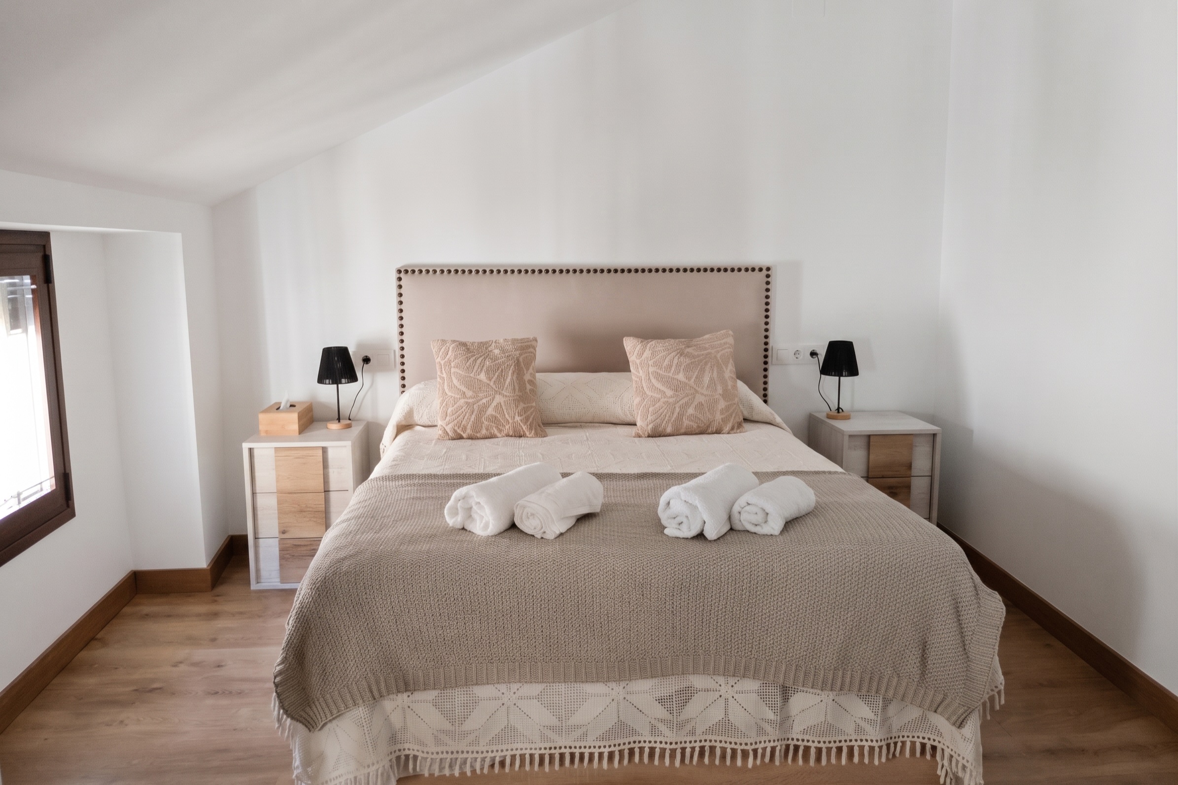 Cama del Ático de frente, con el cabecero tapizado y la colcha de ganchillo