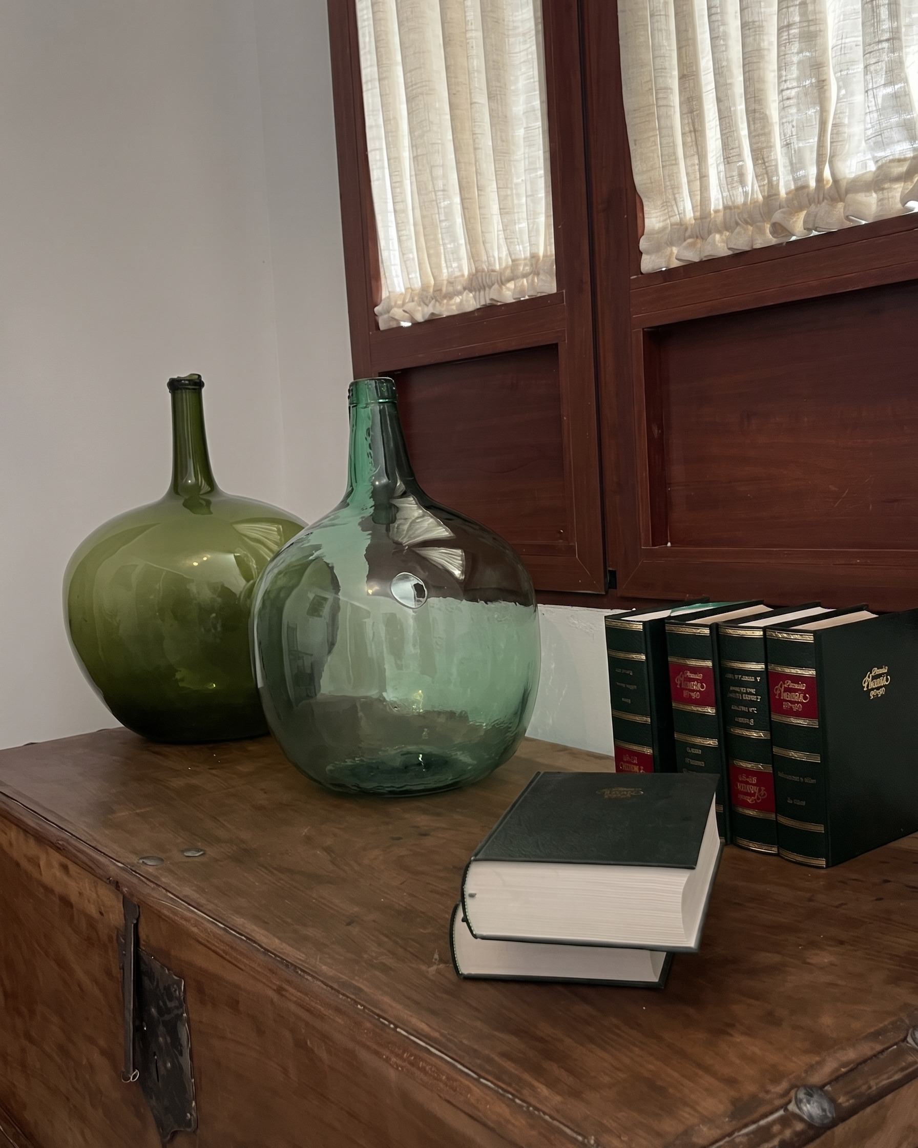 Damajuanas de vidrio junto a una estantería de libros